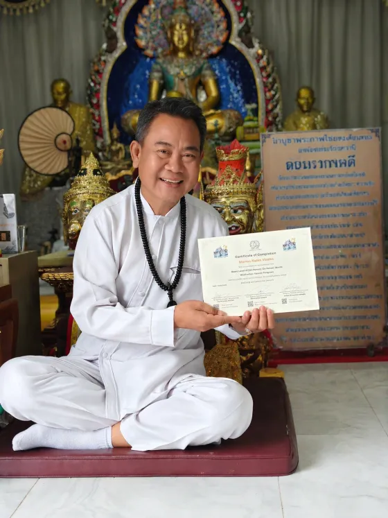 Master Sawan holding a Certificate of Completion at a sacred temple